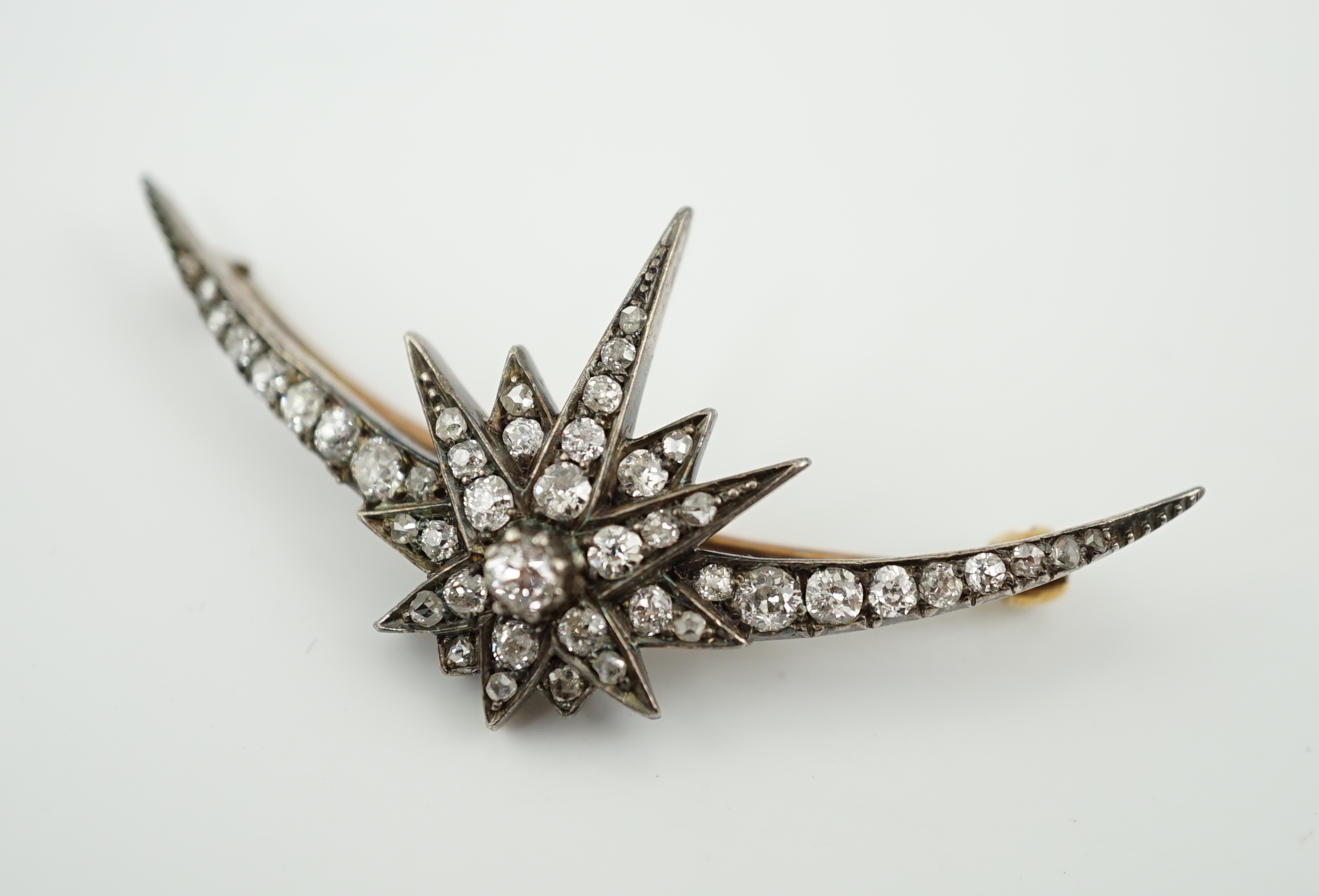 A Victorian gold, silver and graduated diamond cluster set crescent and starburst brooch
